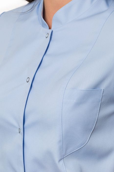 Żakiet medyczny Urszula – dłuższy fason z kołnierzem stójką, zaokrąglonymi kieszeniami i bocznymi rozcięciami dla pełnej swobody ruchów.